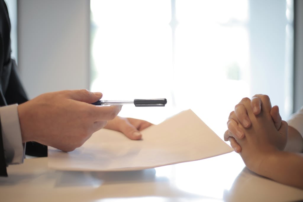 real estate agent giving offer and acceptance to woman to sign