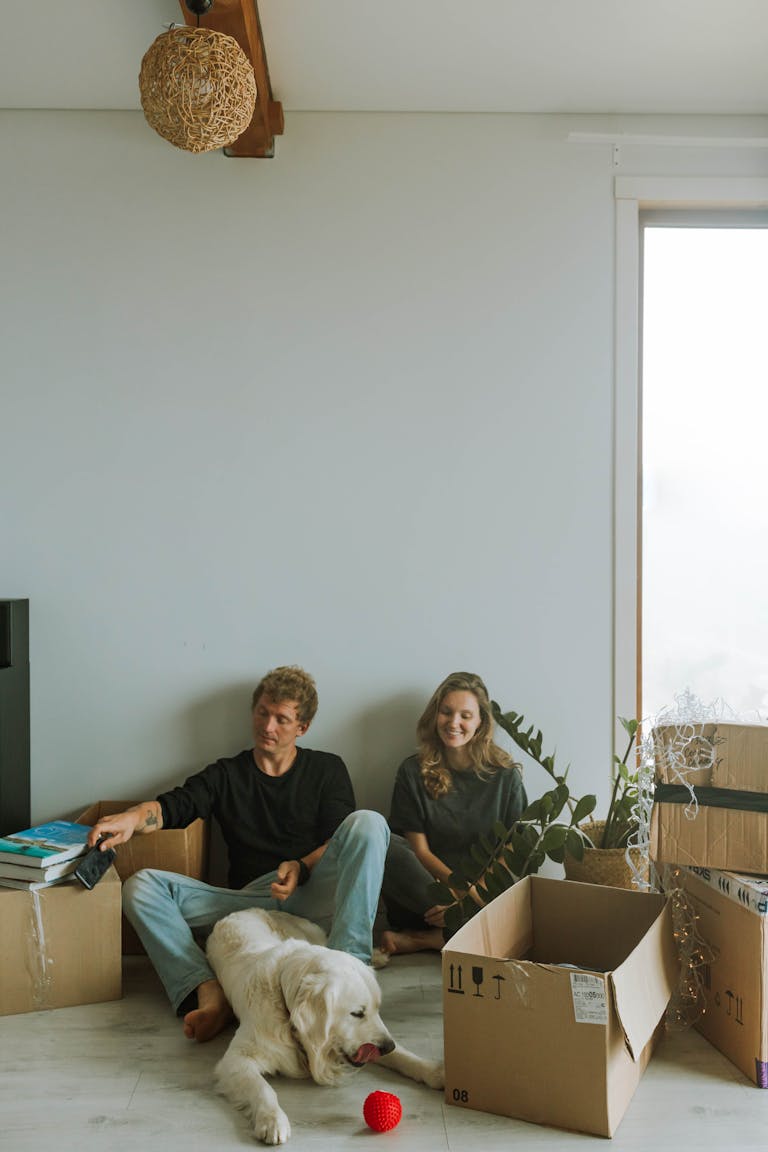 A first home buyer couple Sitting Beside the Boxes in their new home they financed through mortgage broker perth