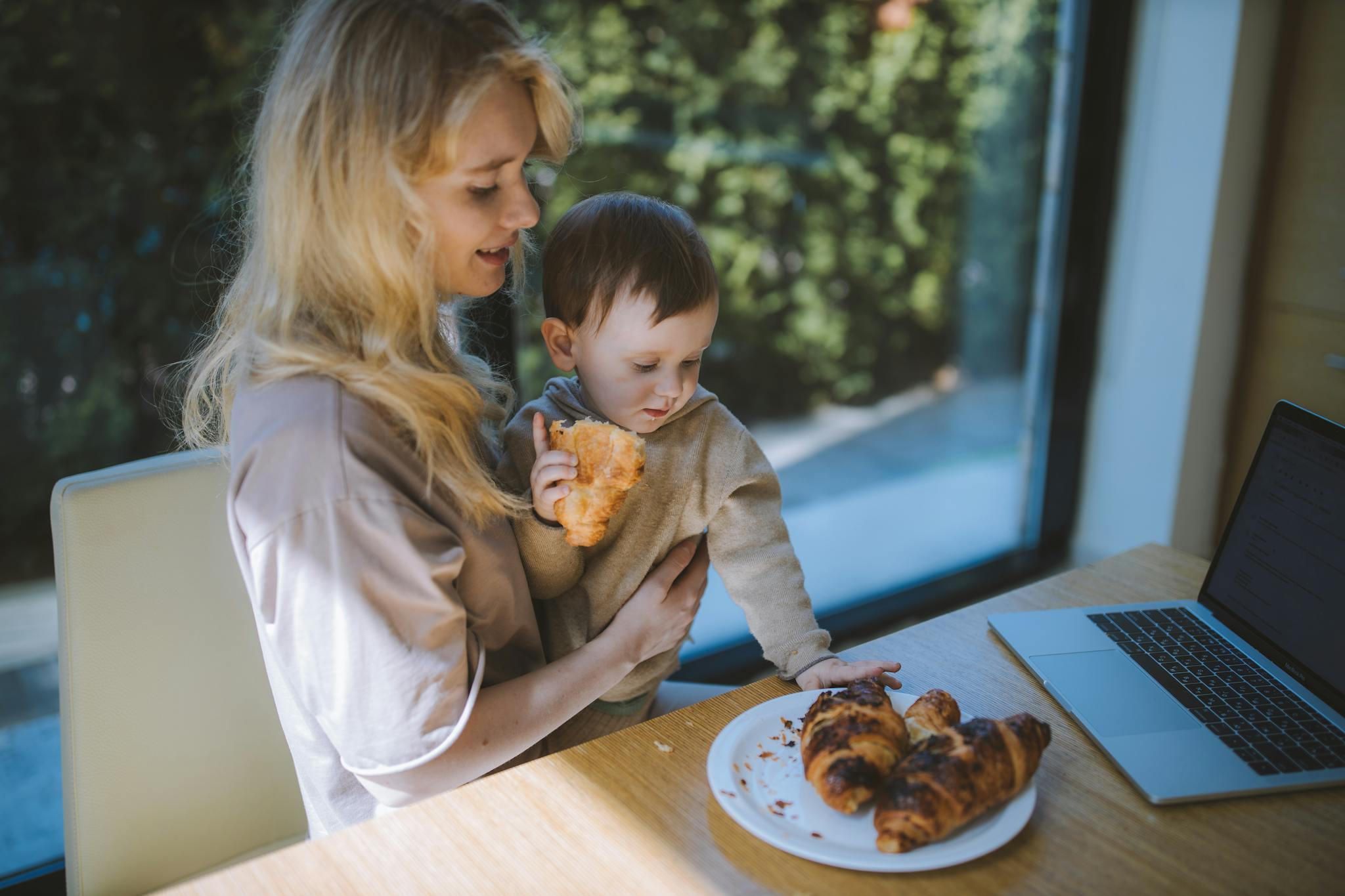 Woman Having Breakfast With her Baby while looking at how to refinance a home loan