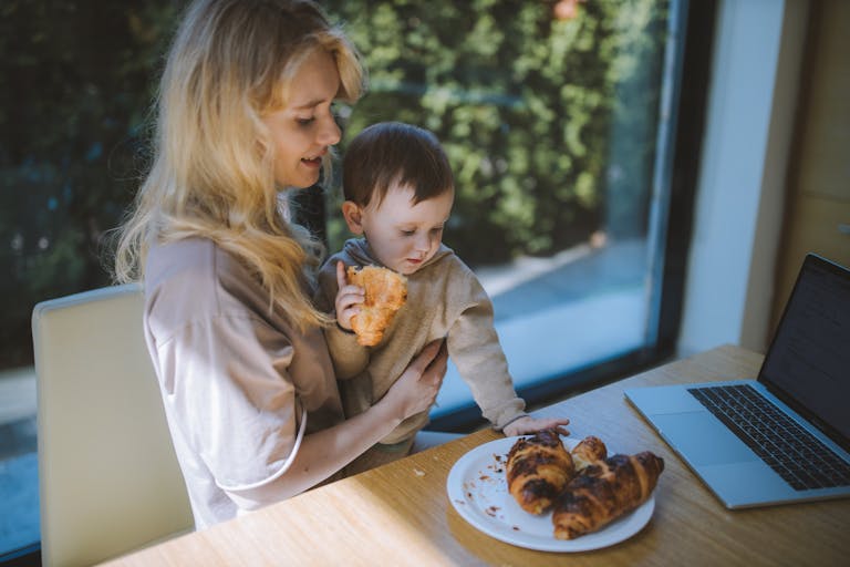 Woman Having Breakfast With her Baby while looking at how to refinance a home loan