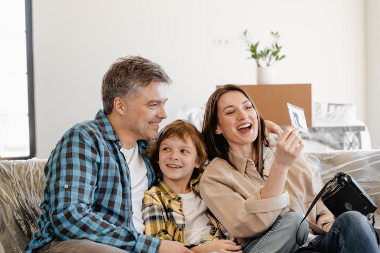 A cheerful family enjoys time together on a couch surrounded by moving boxes in their new home after choosing mortgage brokers instead of bank.