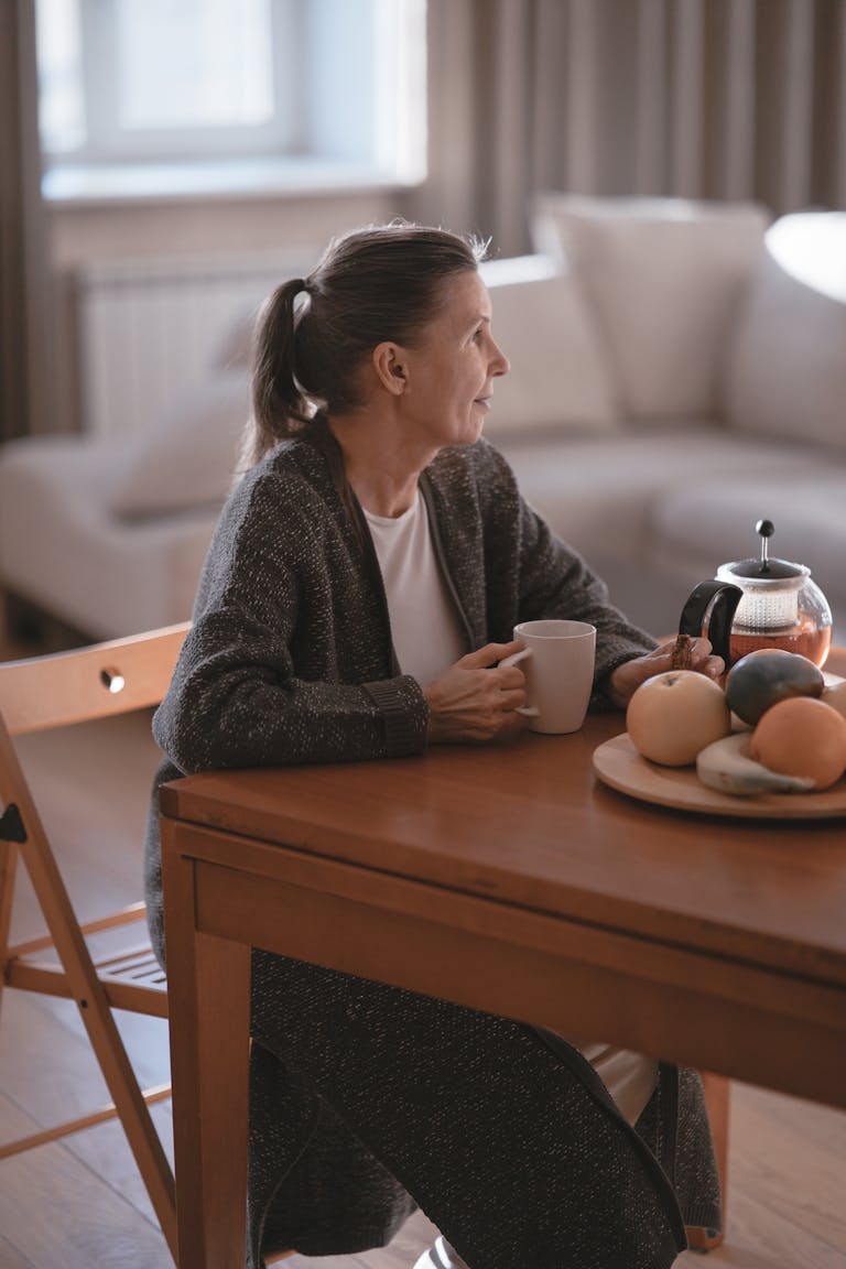 Senior woman enjoying coffee in a cosy home setting, reflecting a peaceful and relaxed moment of leisure while considering a reverse mortgage after speaking with her perth mortgage broker.