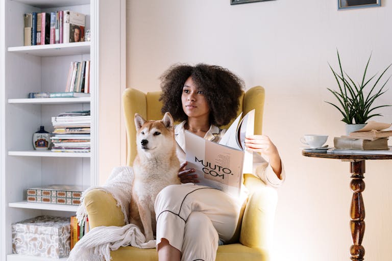 Woman reading a magazine at home with her Shiba Inu dog on a cosy chair after discussing refinancing with her mortgage broke