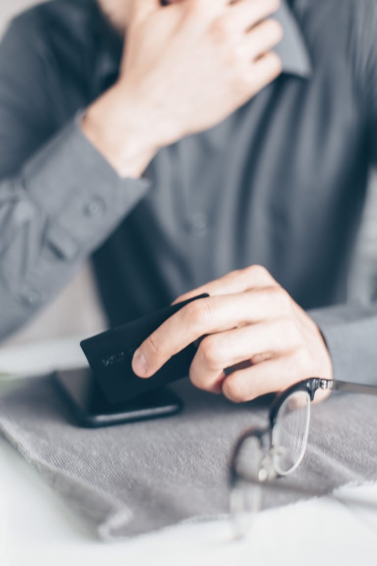 Close-up of a hand holding a credit card above a smartphone on a desk, as homebuyer seeks alternative lending after bad credit