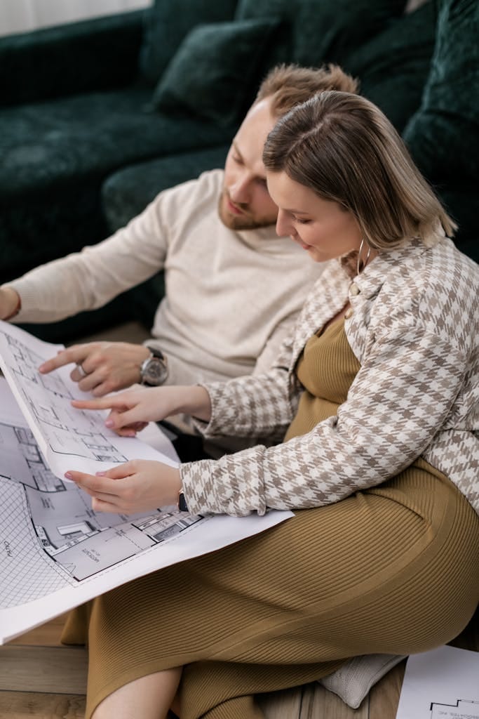 Couple examining architectural blueprints, symbolising home planning or buying process in the perth property market