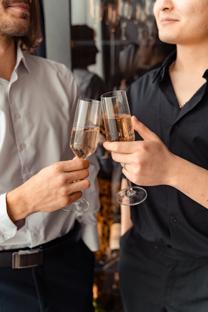 Two adults clinking champagne glasses in a festive indoor setting, capturing a moment of elegance and celebration as the celebrate being mortgage free