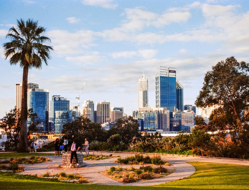 Vibrant skyline of Perth with greenery from King's Park, featuring skyscrapers and a palm tree as buyers question if Perth's property market is falling anytime soon