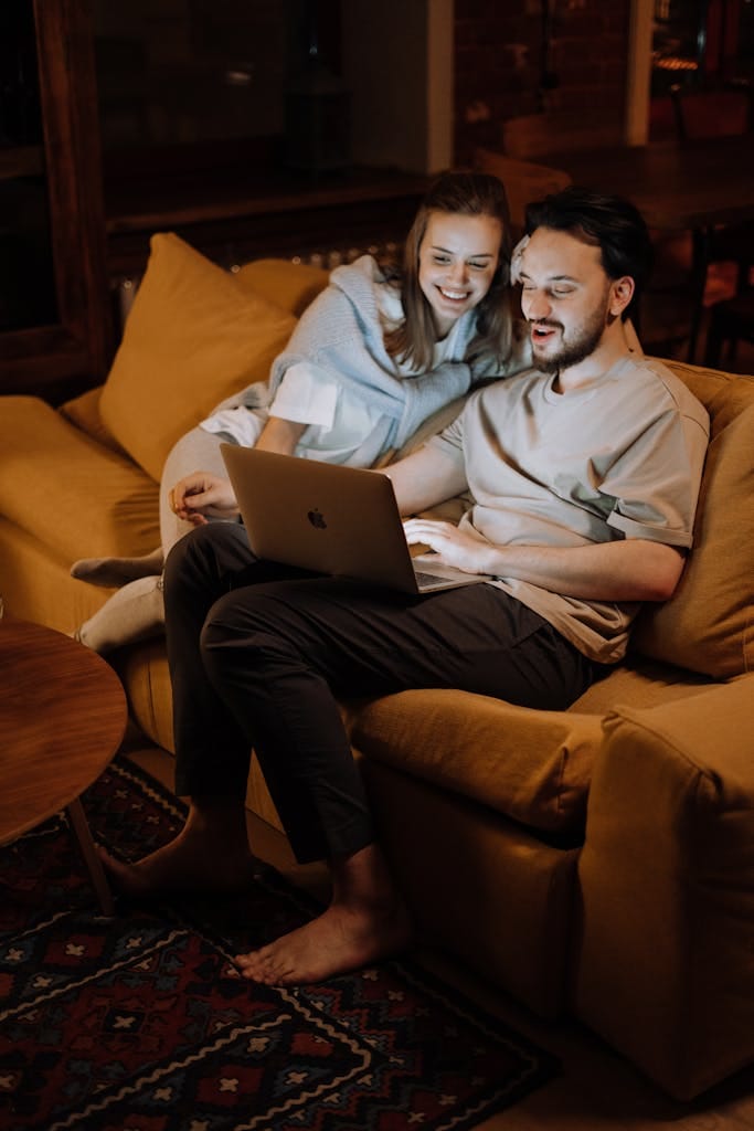 A couple relaxing on a cozy sofa at home using a laptop during the evening looking for first home loan