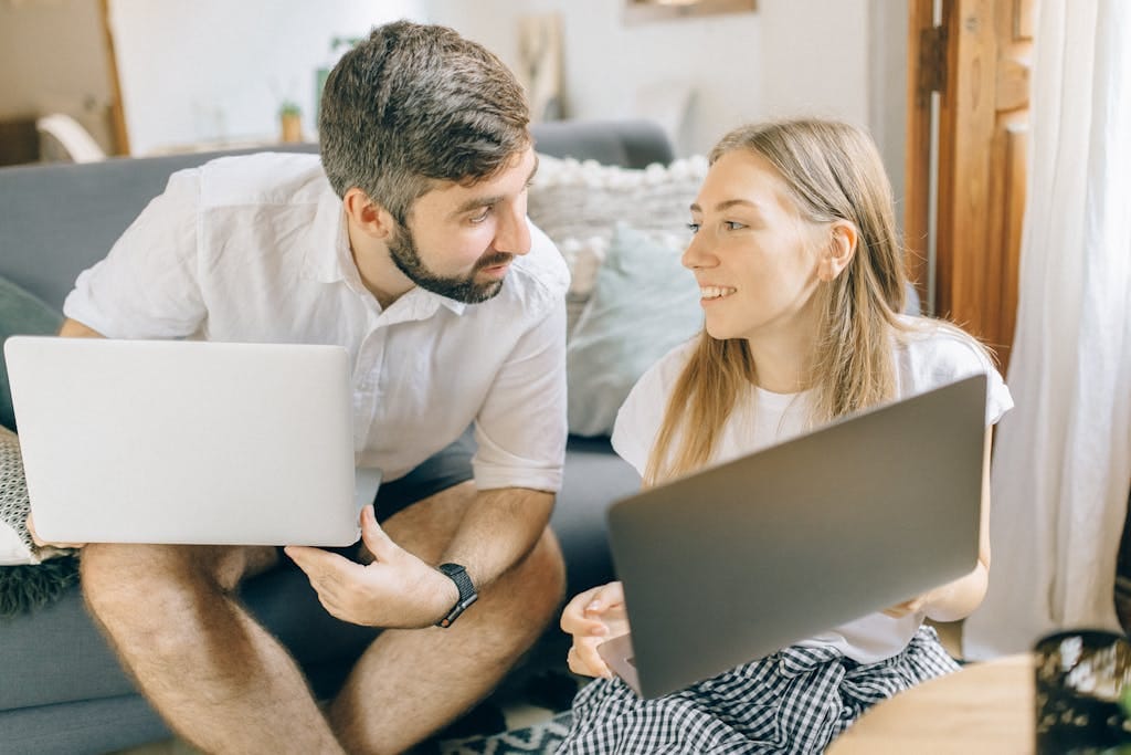 A couple compare refinance options together on their laptops in a cosy living room in Perth