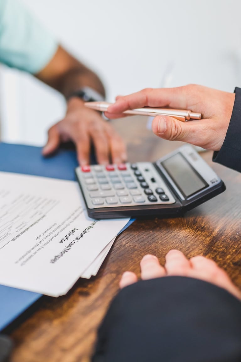 Hands working with a calculator and documents at a meeting with mortgage broker to determine borrowing capacity perth.