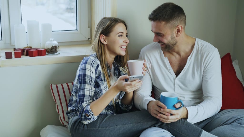 first home buyer couple enjoying coffee and conversation indoors by the window after calling mortgage broker perth