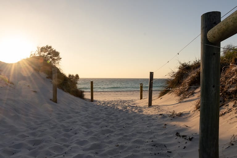 Tranquil pathway leading to Cottesloe Beach at sunset with soft sand and ocean view mortgage broker perth