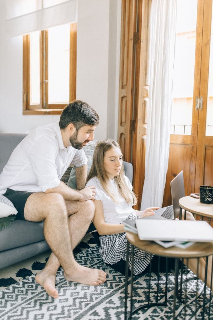 A young couple research home loan options while working from their cozy home environment.