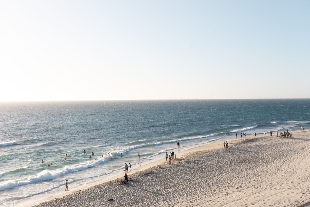 Tranquil aerial view of Cottesloe Beach in Perth with people enjoying the sunny seashore and crashing waves amid talk of perth property downturn