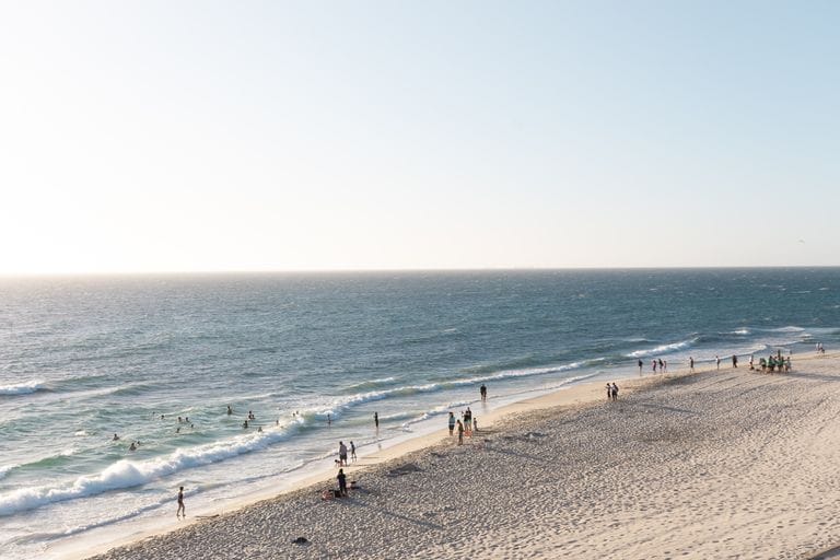Tranquil aerial view of Cottesloe Beach in Perth with people enjoying the sunny seashore and crashing waves amid talk of perth property downturn